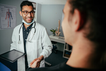 Mixed race male nurse chatting to patient in clinic