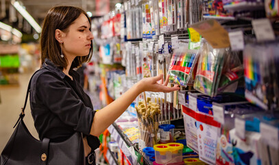 young woman choosing school stationery in supermarket.