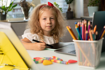 a little girl studies at home, returns to school, the child draws on a graphic tablet