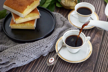 coffee in white cup on white porcelain plate on wooden table.