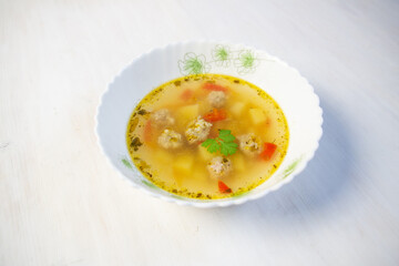 soup with meatballs, potato, spicies in bowl on white background