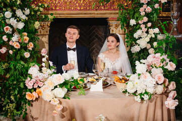 happy bride and groom at the table in the restaurant hall. festive banquet. 