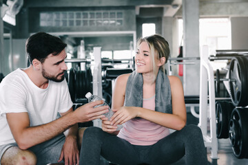 Sport Couple Love Sharing a Bottle of Water Together After Exercised in Fitness Club, Attractive Sporty Young Couple Enjoy Exercising Together in Fitness Gym. Exercise Training and Sport Lifestyles.