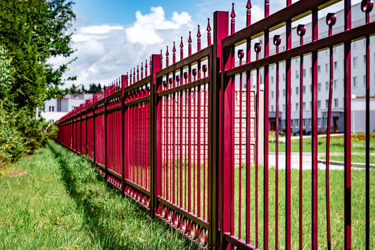 Red decorative cast metal wrought fencing near public bulding.