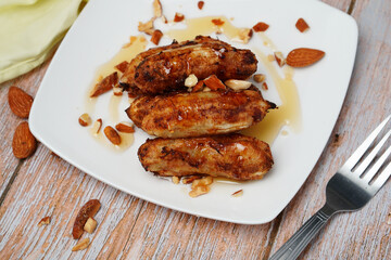 Grilled bananas on a plate. Topped with clear honey and almond seeds