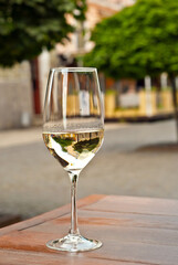 Glass of white wine close up. Alcoholic drink on a wooden table on a background of the city. Transparent wine on the summer terrace of the restaurant.