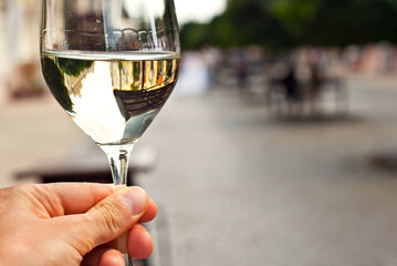 Glass of white wine close up. Alcoholic drink on a wooden table on a background of the city. Transparent wine on the summer terrace of the restaurant.