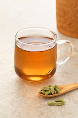 Healthy Cardamom tea  with a spoon green cardamom pods in front  