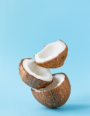 Cracked coconuts on blue background. vertical. copy space - obrazy, fototapety, plakaty