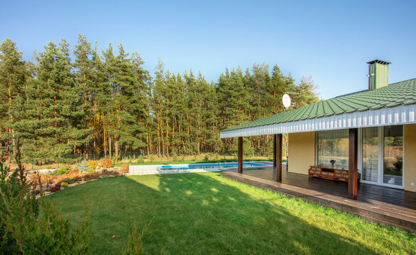 Backyard of a modern country house with a swimming pool. House in forest. Space for text. High quality photo