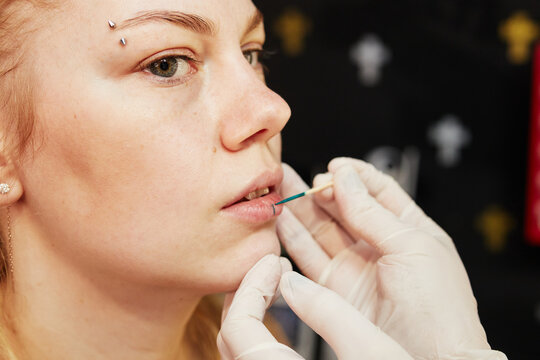 the girl is doing markup for a lip piercing close-up