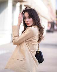 Woman stands in the street in a jacket and jeans