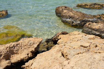 Fototapeta na wymiar Surface of clear water on tropical sandy beach with stones in Crete Greece.