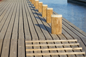 Wooden mooring bollards with shadows on the mole.