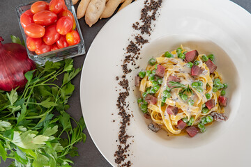 Italian fettuccine carbonara with green peas in a white plate