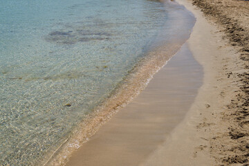 Clear waves and colorful sand on tropical sandy beach in Crete Greece.
