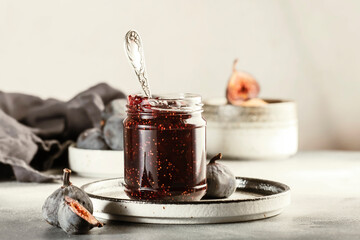 Fig confiture in glass jar. Fresh fruits on gray kitchen table, negative space