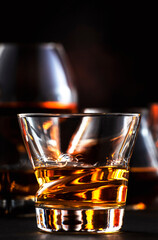 Strong alcohol drinks, hard liquors, spirits and distillates in glasses: cognac, scotch, whiskey and other. Black bar counter background