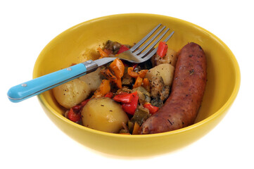 Saucisse fumée avec des pommes de terre et des poivrons servis dans une assiette avec une fourchette sur fond blanc