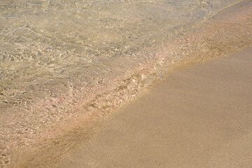 Clear waves and colorful sand on tropical sandy beach in Crete Greece.