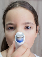 Child girl using medical spray for breath. Inhaler