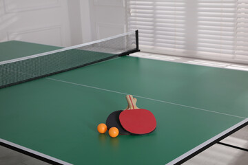 Rackets and balls on ping pong table indoors