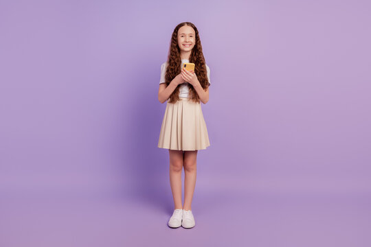 Portrait of nice small girl hold smartphone texting like post share comments on purple background