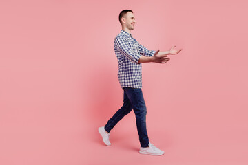 Full length profile side portrait of young handsome guy go walk step happy positive smile open arms hug isolated over pink background