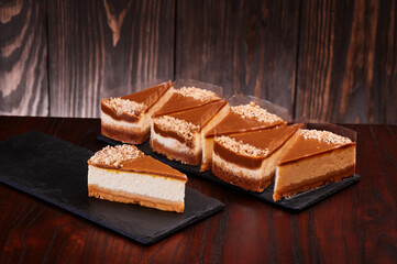 Pieces of cheesecake with chocolate icing on black stone boards. Traditional popular dessert. Space for text. High quality photo