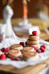 Cheesecakes decorated with cherry on a parchment paper on the table. Sweet home made dessert or breakfast