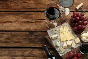 Tasty red wine and snacks on wooden table, flat lay. Space for text