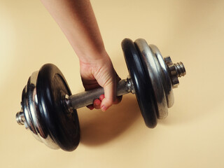 The hand holds a heavy dumbbell for bodybuilding