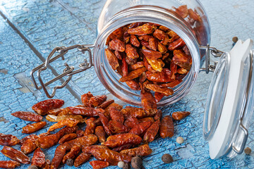 Glass jar overturned on the blue table full of dehydrated cayenne