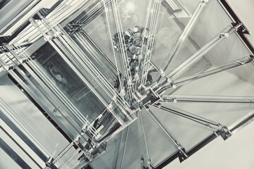 Contemporary metal winding stairs with clear glass steps installed in spacious light hall in...