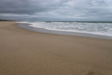 Fototapeta na wymiar Sand and surf on an overcast day