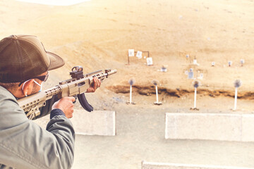 Men practicing shooting with a assault rifle at target. Selective Focus