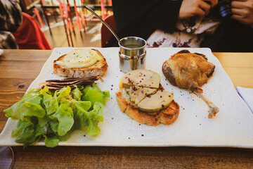Selective focus on duck confit  served with foie gras (goose liver), salad and cheese