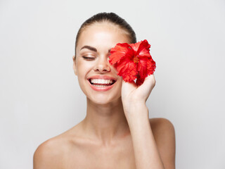 cheerful woman with red flower near face cosmetics naked shoulders