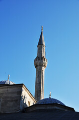 Fototapeta na wymiar High minaret and mosque. View of the mosque against the blue sky. Summer sunny day.
