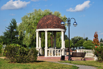 Summer gazebo with columns in the park. Panorama of the city park with a gazebo, a lantern and a...