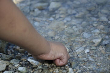 a child touching the rocks near the lake.