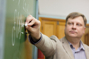 Professor of the Department of Applied Mathematics in classroom at the blackboard writes formulas...