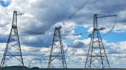 high voltage power line towers against the background of cumulus clouds