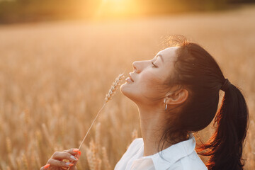 Portrait of a beautiful brunette woman with ears of wheat on her face.