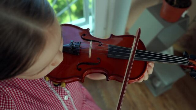 Little girl 5 years old in a red dress plays the violin. Slow motion.