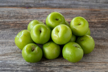 fresh green plums on wood background