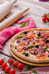 Juicy pizza with sausages, tomatoes and olives on a white wooden background. Space for text. High quality photo