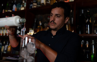 cocktail man pouring drink into shaker

