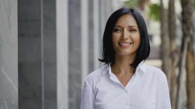 Portrait video face Charming beautiful woman standing smiling happy in city. business woman positive thinking. Latin women feel confident enjoying in health of healthy teeth. looking at camera