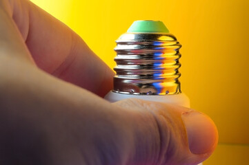 the hand is holding a LED lamp with an e14 base illuminated in different colors.